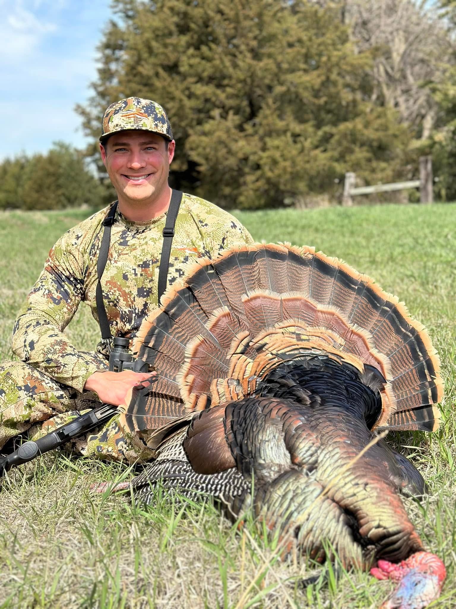 Hunter with a Nebraska turkey in spring green field